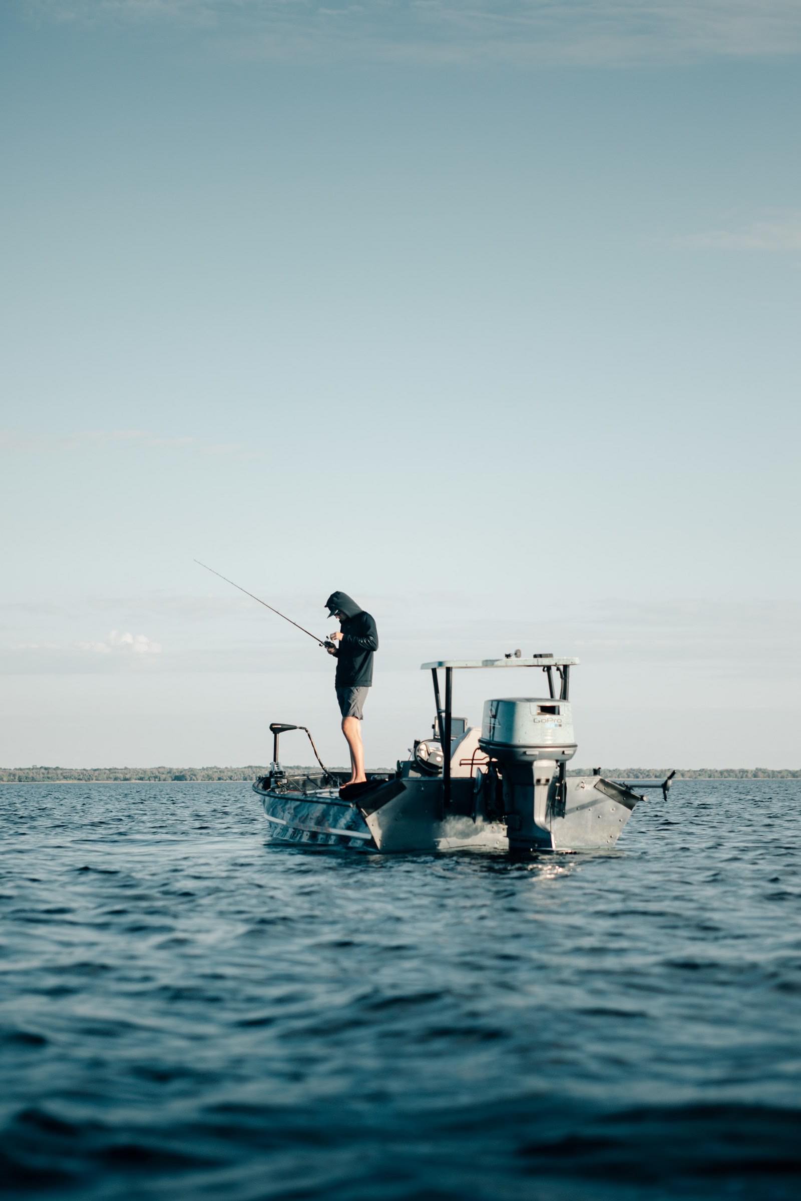 An angler working a rod from a boat on open blue water