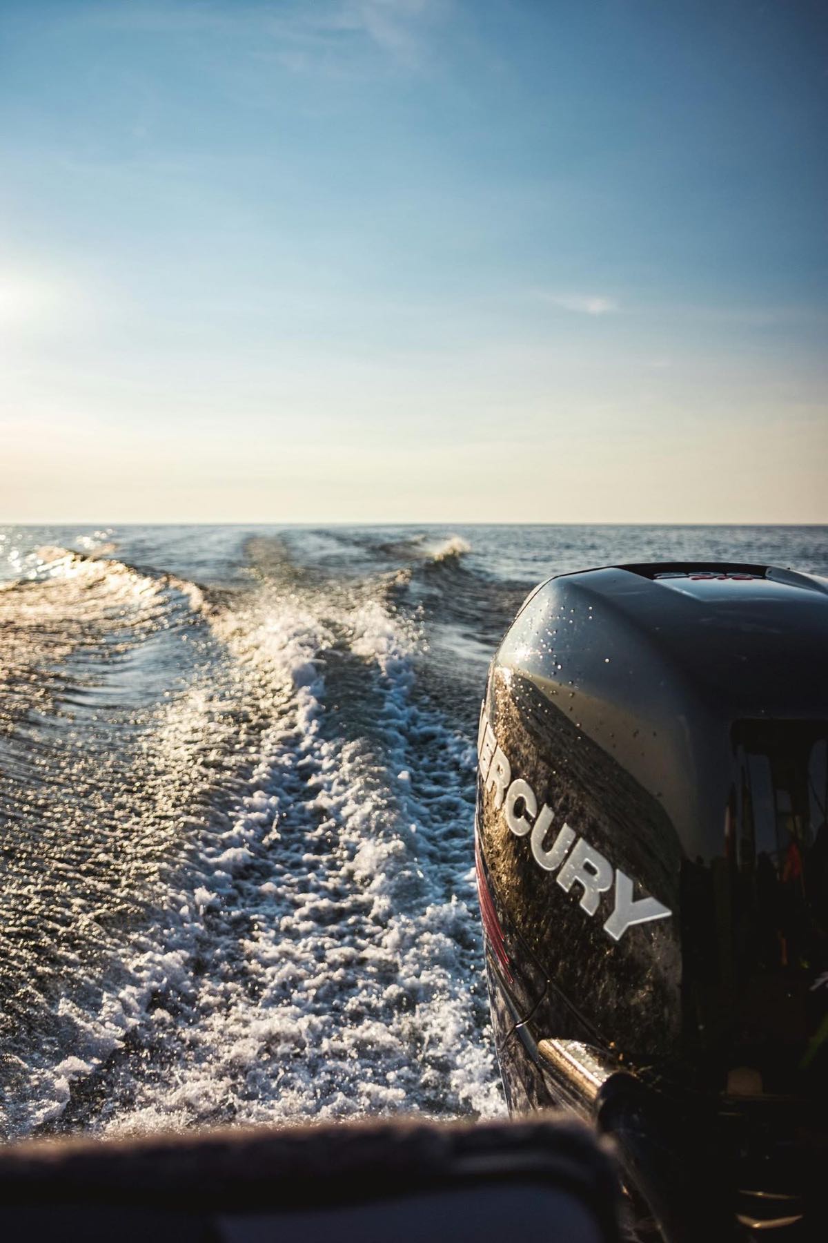 Mercury outboard over a churning wake at golden hour